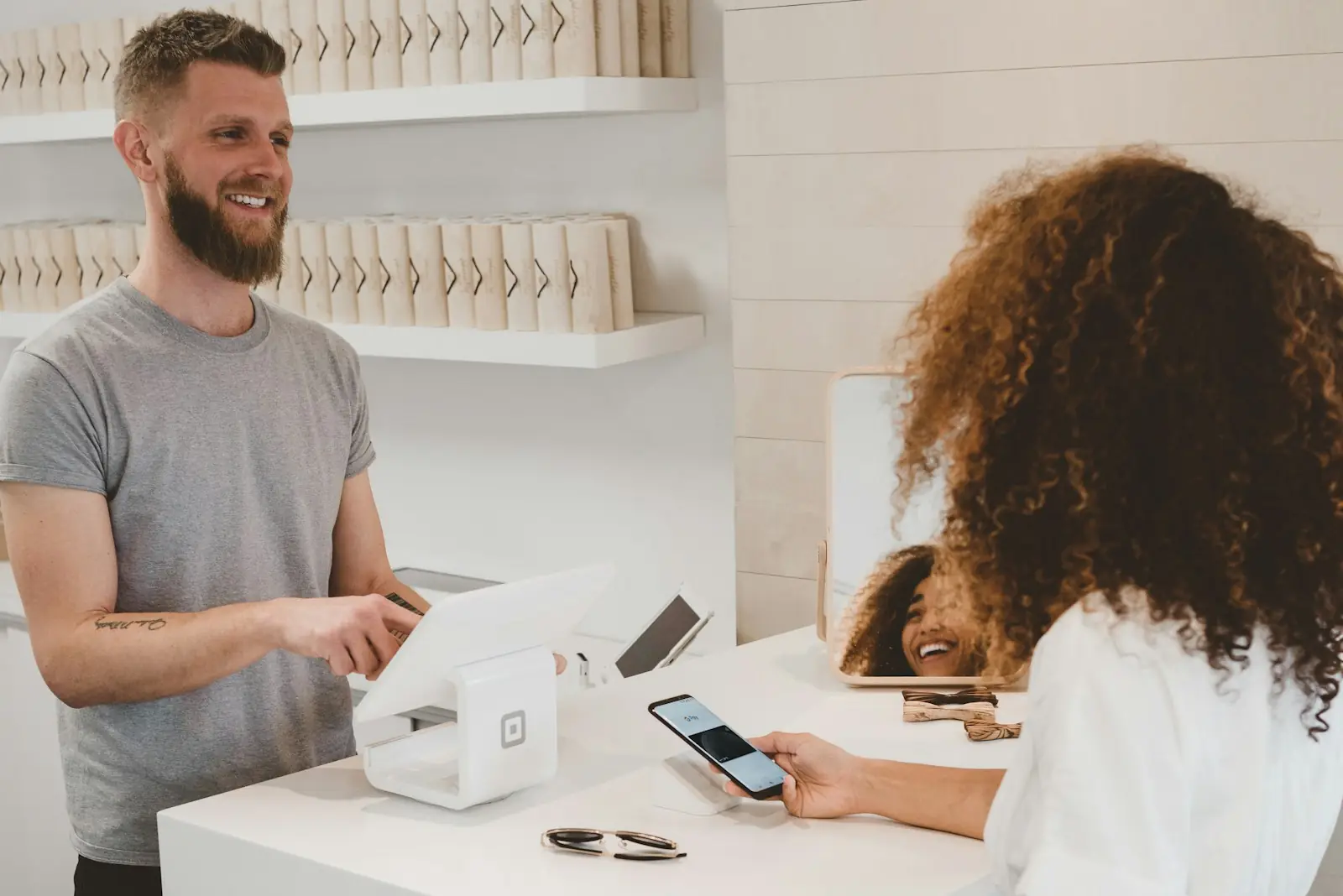 Atendente de loja sorrindo para uma cliente no balcão
